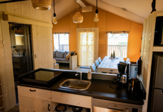 Vue intérieure d'une tente glamping de luxe avec cuisine moderne et salle à manger à Noord-Brabant.