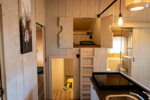 Indvendig udsigt over Glamping De Rode Vos telt, moderne interiør med seng og lille badeværelse.