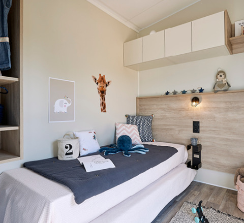 Modern, cozy children's bedroom at Camping Les Charmes - Cottages Dordogne with playful decor and plush toys.