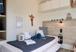 Moderne, sfeervolle kinderkamer in Camping Les Charmes - Cottages Dordogne met vrolijke decoratie en speelgoed.