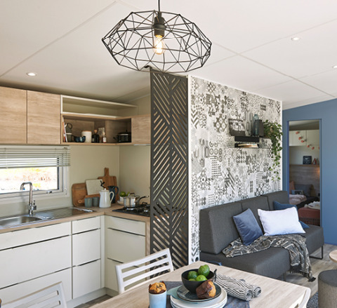 Vista interior de una moderna casa glamping en Camping Les Charmes, Dordogne, con cocina y sala de estar.