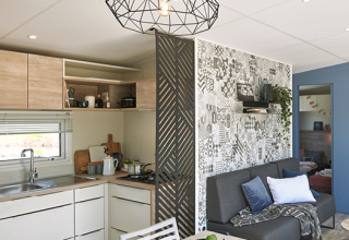 Vue intérieure d’un cottage glamping moderne au Camping Les Charmes en Dordogne avec cuisine et salon lumineux.