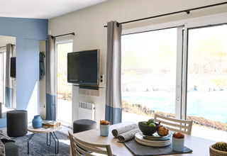 Hébergement glamping moderne avec coin repas, TV et grandes baies au Camping Les Charmes - Cottages Dordogne.