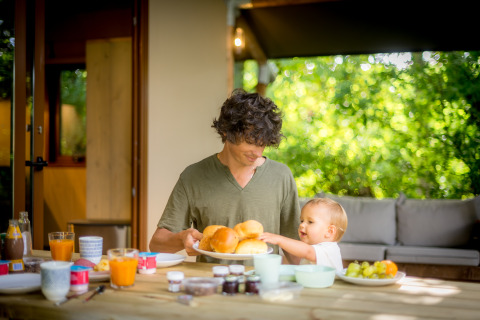 Padre e hijo disfrutan de un desayuno al aire libre en Urban Gardens Ieper - Glampingtenten West-Vlaanderen.