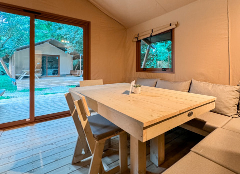 Innenansicht eines Glampingzelts mit Holztisch und Sitzbank bei Urban Gardens Ieper, West-Vlaanderen.