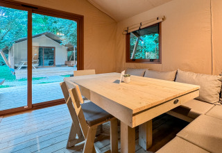 Interior view of glamping tent with wooden table and seating at Urban Gardens Ieper, West-Vlaanderen, Belgium.