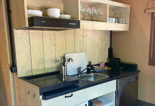 Cocina de glamping moderna en Urban Gardens Ieper con paneles de madera, lavavajillas y estantes abiertos.