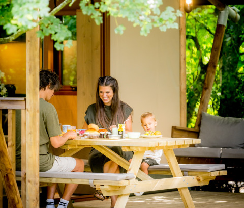 Family having breakfast outside a glamping tent at Urban Gardens Ieper in West Flanders, Belgium.