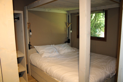 Cama cómoda con ventana en el interior de Urban Gardens Ieper - Glampingtenten West-Vlaanderen.