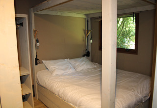 Comfortabel bed en raam in het interieur van Urban Gardens Ieper - Glampingtenten West-Vlaanderen.