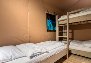 Interno di una tenda glamping presso Urban Gardens Ieper, Fiandre Occidentali, con letti a castello e finestra.