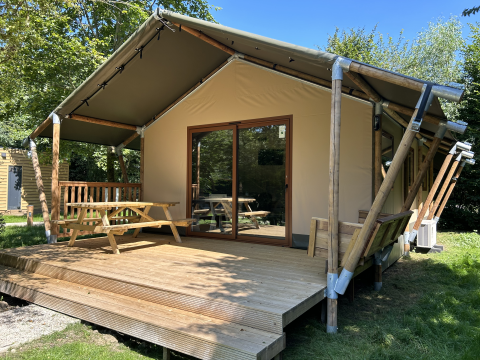Glampingtent van Urban Gardens Ieper in West-Vlaanderen met houten terras en picknicktafels in de natuur.