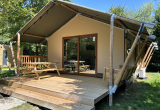 Glampingtent bij Urban Gardens Ieper in West-Vlaanderen met houten terras en picknickbank in het groen.