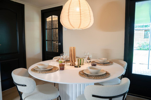 Zona pranzo moderna al glamping Camping Twente - Chalet Overijssel, tavola apparecchiata per quattro persone.