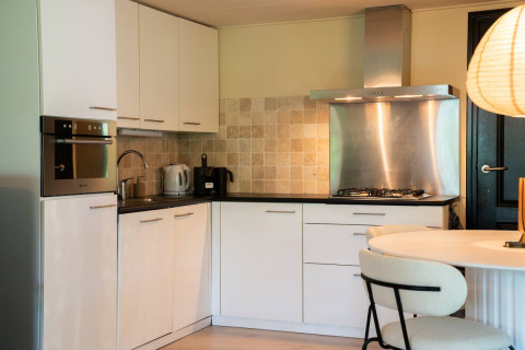 Cucina moderna per glamping nel Chalet Overijssel di Camping Twente con pensili bianchi ed elettrodomestici.