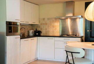 Modern camping kitchen in Chalet Overijssel at Camping Twente with white cabinets and stainless appliances.
