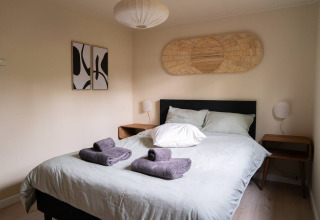 Modernes Schlafzimmer mit Doppelbett, Handtüchern und Dekor in Chalet Overijssel auf Camping Twente.