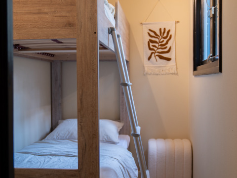 Knusse kamer met stapelbed, ladder, wanddecoratie en raam bij Camping Twente - Chalet Overijssel.