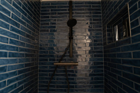 Doccia moderna con piastrelle blu scuro presso alloggio glamping Camping Twente - Chalet Overijssel.