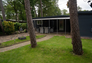 Glamping accommodation at Camping Twente - Chalet Overijssel features a covered terrace and lush garden.