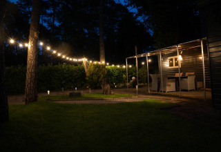Scena serale all'aperto con luci a Camping Twente - Chalet Overijssel, sistemazione glamping confortevole.