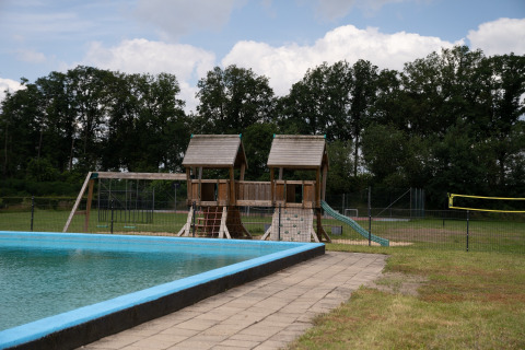 Outdoor camping site with playground, swimming pool, and volleyball net at Camping Twente - Chalet Overijssel.