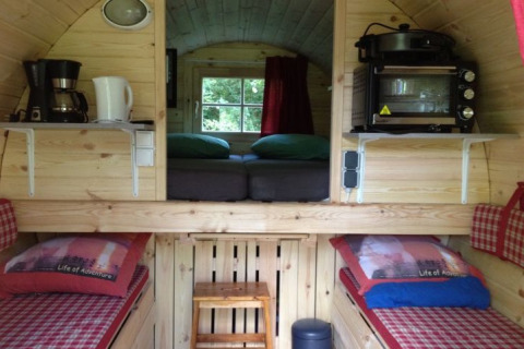 Vista interna di un alloggio glamping con pannelli in legno, letti e angolo cottura a Zeeland.