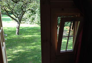 Uitzicht vanuit glamping accommodatie bij Minicamping De Bokkepsprong - Wijnvaten in Zeeland met geopend raam.