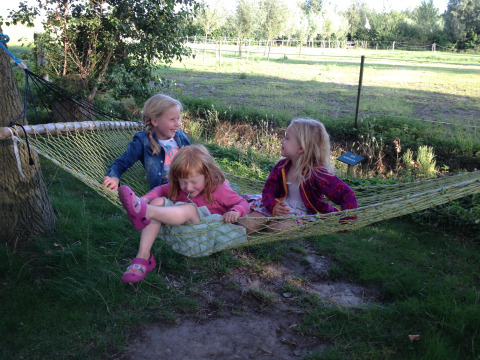 Tres niños jugando juntos en una hamaca en Minicamping De Bokkepsprong - Wijnvaten en Zeeland, Países Bajos.