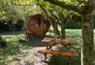 Glampinghut bij Minicamping De Bokkepsprong in Zeeland, met picknickbank onder bomen in het groen.