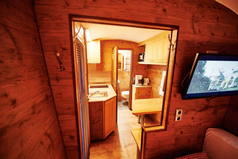 Interieur van een knusse glampingaccommodatie bij Handwerkerhof Fränkische Schweiz Zigeunerwagen met houten afwerking.