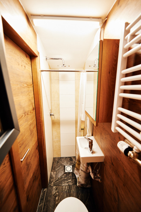 Bagno stretto con pannelli in legno, doccia, WC e piccolo lavandino nel glamping Handwerkerhof Fränkische Schweiz Zigeunerwagen.