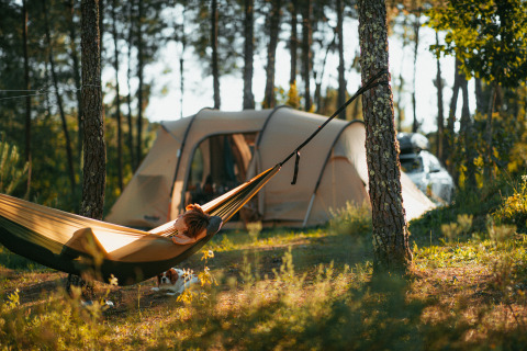 Persona descansando en una hamaca junto a una tienda glamping en el bosque de Lima Escape - Boomlodges en Portugal.