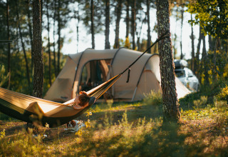 Persoon ontspant in een hangmat bij een glampingtent in het bos bij Lima Escape - Boomlodges in Portugal.