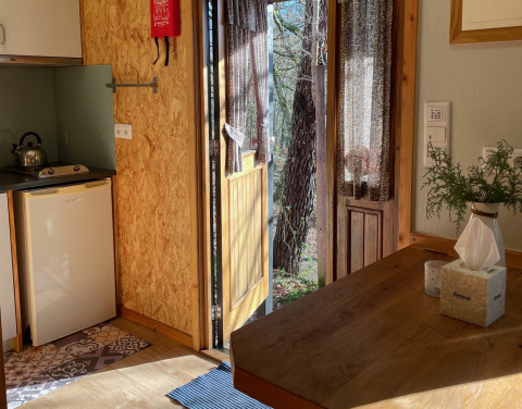 Interior of Lima Escape glamping Portugal with open door to nature, sunlight, and wooden furniture.