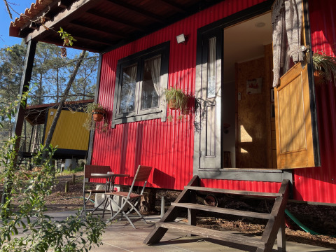 Glamping accommodation at Lima Escape, Portugal, featuring colorful boomlodges, patio seating, and forest.
