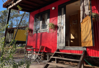 Glampingaccommodatie Lima Escape in Portugal met kleurrijke boomlodges, terrasstoelen en bosomgeving.