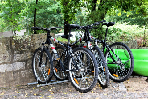 Trois vélos tout-terrain garés près d’un kayak vert dans le glamping Lima Escape au Portugal.