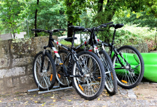 Tre mountainbikes parkeret ved siden af en grøn kajak på Lima Escape glampingplads i Portugal.