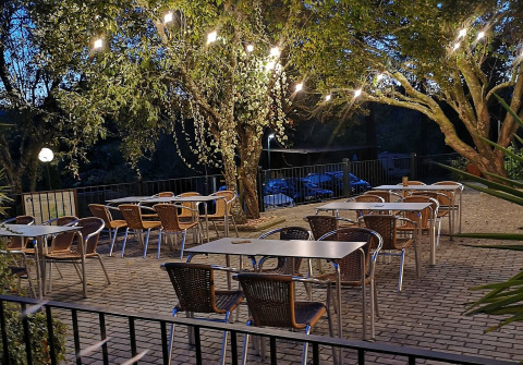 Terraza al aire libre de Lima Escape glamping con mesas, sillas y luces colgadas entre árboles al atardecer.