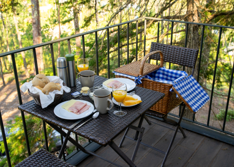 Frühstück auf dem Balkon bei Lima Escape Boomlodges in Portugal mit Brötchen, Saft und Picknickkorb.