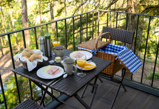 Outdoor breakfast on balcony at Lima Escape Boomlodges in Portugal with coffee, juice, and picnic basket.