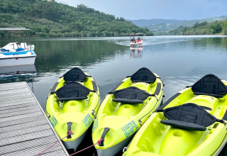 Quattro kayak gialli attraccati a un molo su un fiume calmo, presso Lima Escape Glamping in Portogallo.