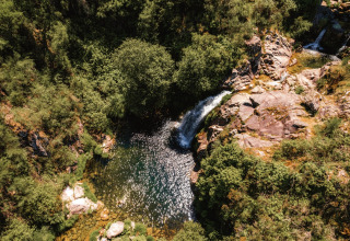 Vista aerea del Lima Escape Boomlodges e tende glamping in Portogallo, immersi nel verde e vicino a una cascata.