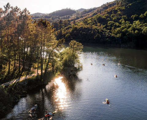Kajakker sejler på en flod omgivet af grønne bakker og træer nær Lima Escape - Boomlodges og Glamping i Portugal.