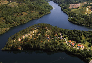 Luftaufnahme von Lima Escape Glamping in Portugal, umgeben von Fluss, Bäumen und grüner Natur.