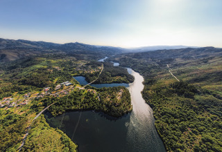 Vue aérienne de Lima Escape Boomlodges et tentes glamping au Portugal, entourées de rivière et de collines.