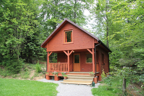 Casetta in legno rossa per glamping di lusso a Camping Isny, immersa nei boschi del Baden-Württemberg.