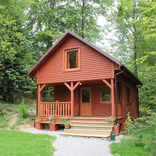 Rode houten hut voor luxe glamping bij Camping Isny, midden in het bos van Baden-Württemberg.
