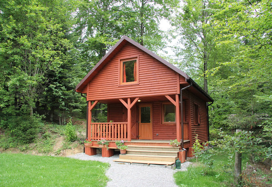 Casetta in legno rossa per glamping di lusso a Camping Isny, immersa nei boschi del Baden-Württemberg.